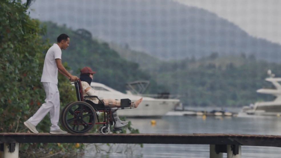 Três Graças: Claudia é levada por enfermeiro para pegar sol — Foto: Globo