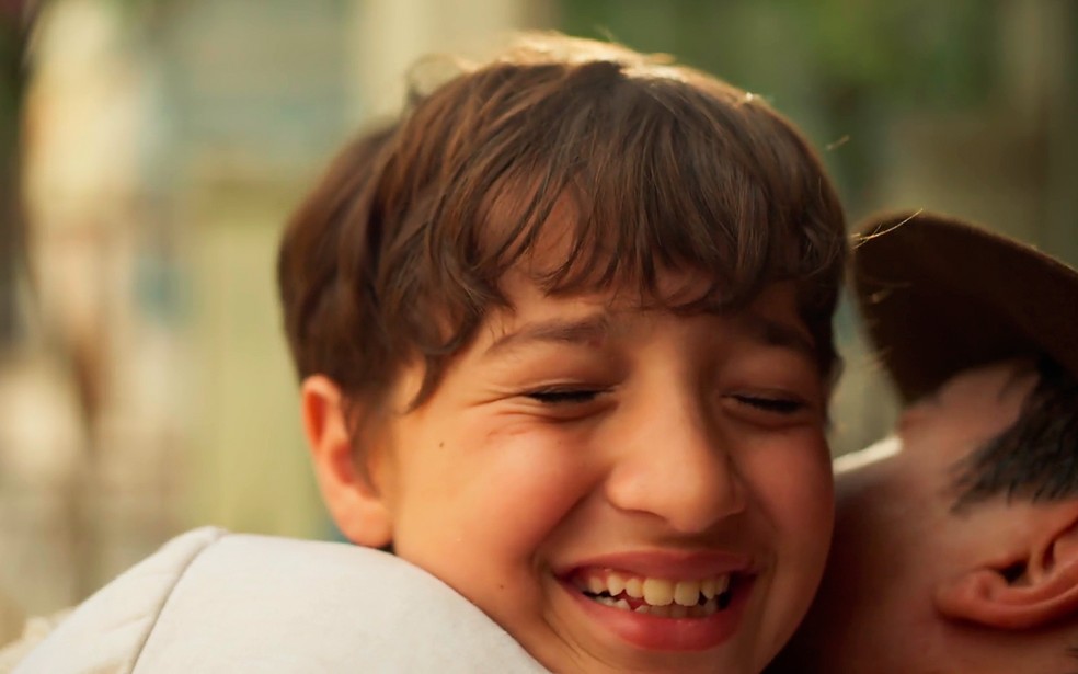 Samir (Davi Malizia) fica radiante ao saber que Candinho (Sergio Guizé) é seu pai - Êta Mundo Melhor! — Foto: Globo