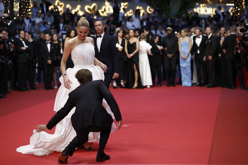 Robert Pattinson ajeita barra do vestido de Jennifer Lawrence no tapete vermelho de Cannes — Foto: Reuters