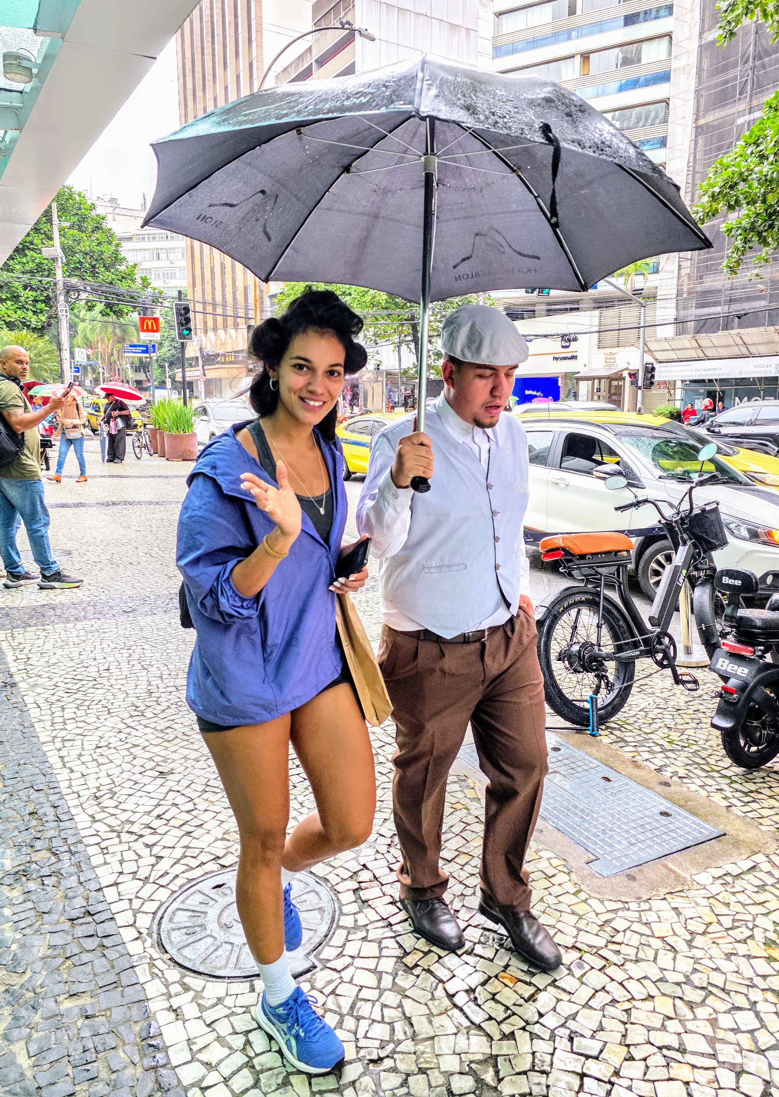 Alane Dias surge de bobs no cabelo pelas ruas do Leblon e pede carona para se proteger da chuva