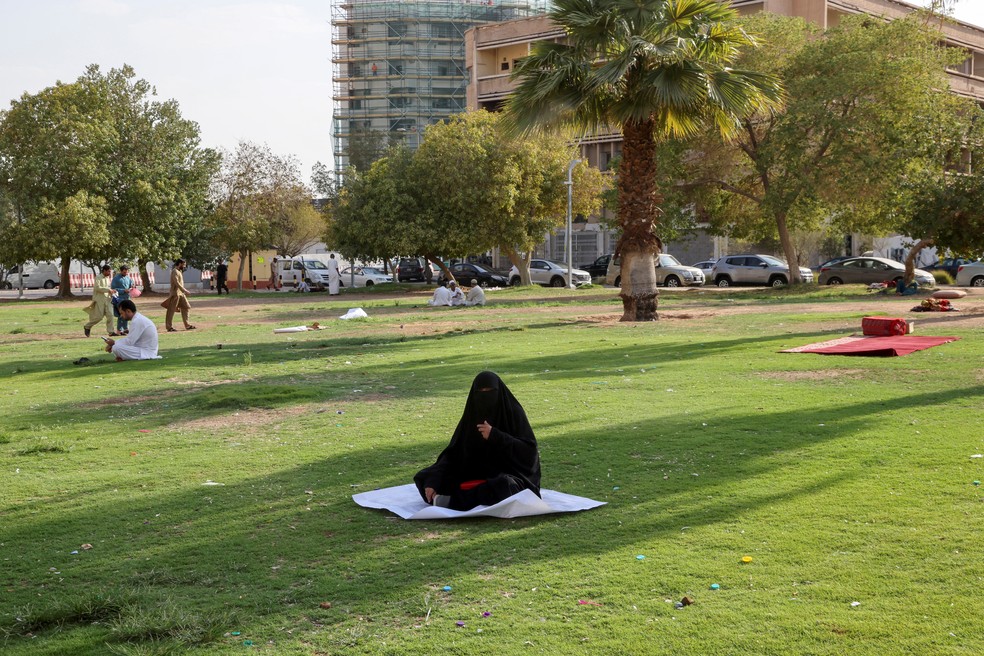 Uma mulher sentada na sobra de uma árvore em Riyadh, Arábia Saudita — Foto: REUTERS/ Ahmed Yosri