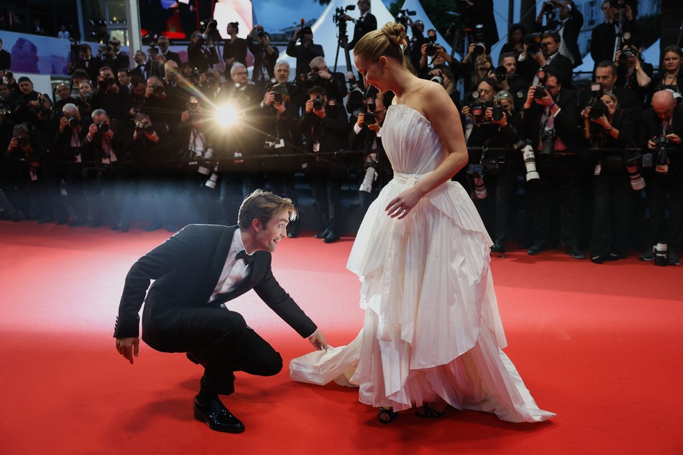 Robert Pattinson ajeita barra do vestido de Jennifer Lawrence no tapete vermelho de Cannes — Foto: Reuters