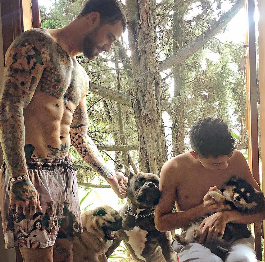 Felipe Titto posa sem camisa com o filho e seus cachorros