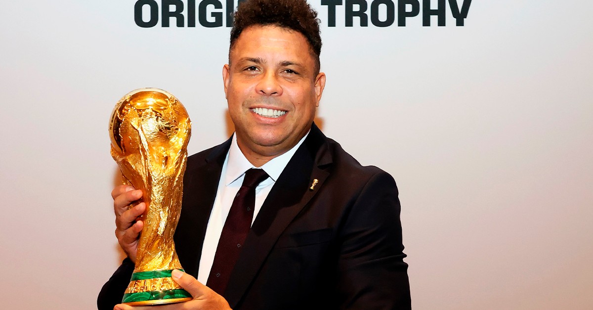 Ronaldo Fenômeno comemorando seus 50 anos ao lado de uma taça de futebol