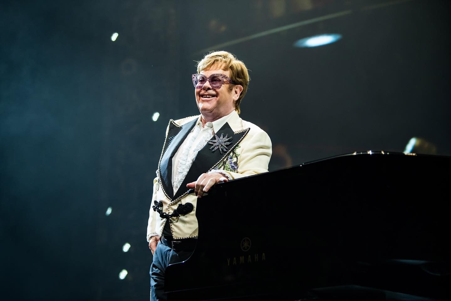 Elton John performando em palco com iluminação colorida